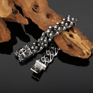 Detail of vintage skull bracelet in stainless steel on driftwood over black mirror surface