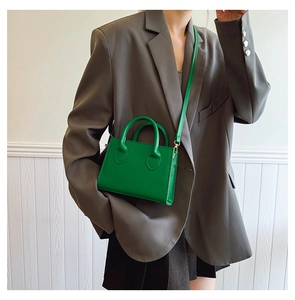 Green mini crossbody bag worn by a model in a grey suit jacket for casual daily style
