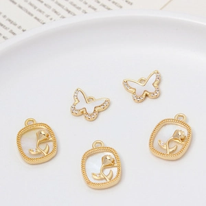 Detailed view of DIY shell butterfly and flower charms in gold with sparkling zircons