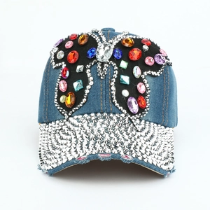 Détails du papillon en strass colorés et des clous argentés sur la casquette en jean