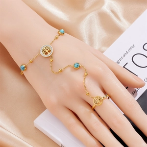 Close-up of gold chain ring bracelet set with turquoise beads and Tree of Life charm