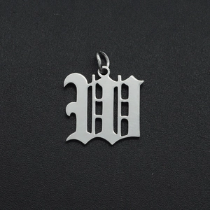 Macro shot of silver Old English letter M charm in stainless steel on textured background