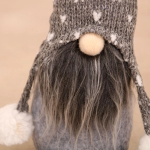 Close-up of a grey knitted gnome hat with white heart patterns and plush pom-poms