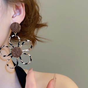 Gros plan de la boucle d'oreille fleur léopard en tissu avec détail tricoté marron