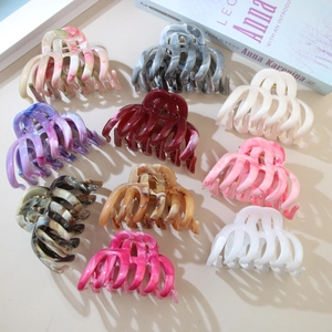 Various marble pattern ABS hair claws displayed on a neutral background with a book