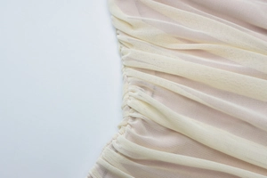 Macro shot of cream mesh fabric showing detailed side ruching on a cutout summer dress