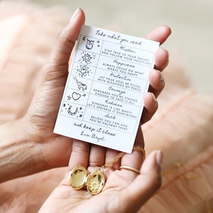 Close-up of golden oval locket necklace with sun engraving and inspirational message card