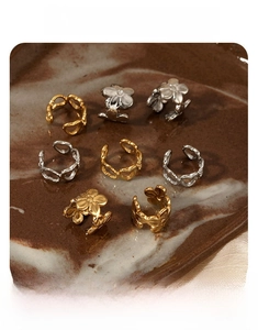 Macro detail of gold and silver ear cuffs with heart and flower cutouts on stone