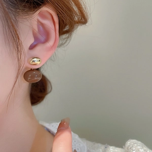 Gros plan d'une boucle d'oreille plaquée or avec perles de résine ambrée sur un mannequin
