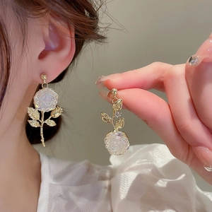 Detail of elegant gold rose earrings with iridescent petals on a female model