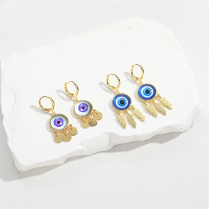 Retro Evil Eye drop earrings in gold with purple and blue charms on gypsum block
