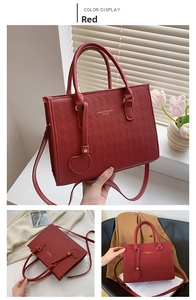 Detail of red quilted tote bag featuring a heart pendant and dual carry handles