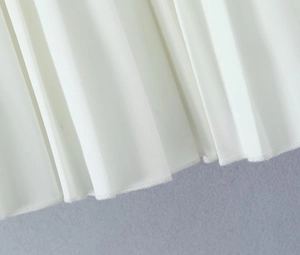 Detailed view of white pleated skirt fabric with precise hem stitching and clean texture