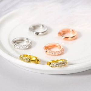 Micro paved zircon hoop earrings in gold, silver, and rose gold on a ceramic tray