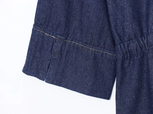 Detail of dark blue denim shirt cuff with contrast gold stitching and side slit
