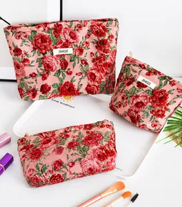 Set dettagliato di tre borse da trucco jacquard con motivi a rose rosse e chiusura a zip
