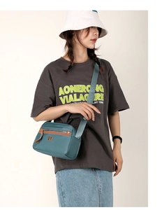 Close-up of lightweight nylon crossbody bag in teal with colorful fox strap and brown trim