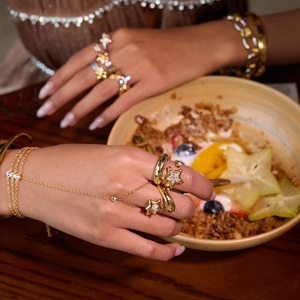 Detail of gold star rings with hammered texture and zircon crystals on hand