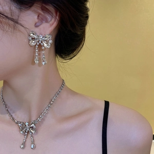 Detail view of full zircon bowknot earrings and necklace set on a female model