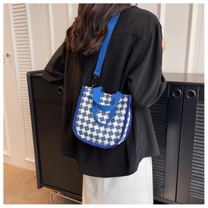 Rear view of a blue and white checkered canvas crossbody bag worn by a model in a room
