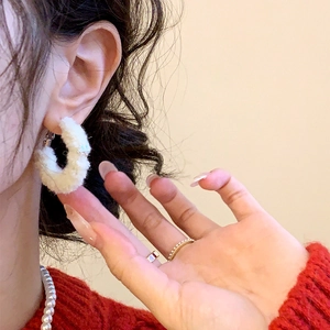 Detail of cream white flocked hoop earrings on a model with warm winter jewelry style