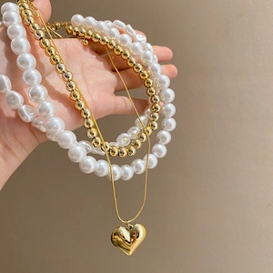 Gros plan sur un ensemble de collier à pendentif cœur doré et chaîne de perles
