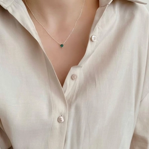 Close-up of S925 silver necklace with heart-shaped green gemstone pendant on model