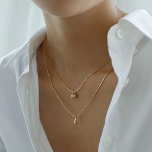 Detail shot of a double-layer gold necklace featuring angel eye and water drop pendants