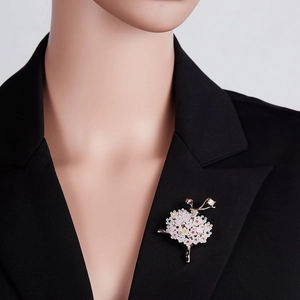 Detailed close-up of a ballerina brooch with white floral skirt on a black suit jacket