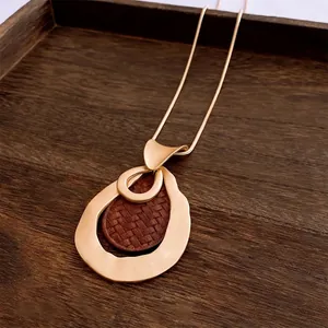 Vintage gold hollow water drop pendant necklace with brown leather inlay on wood tray