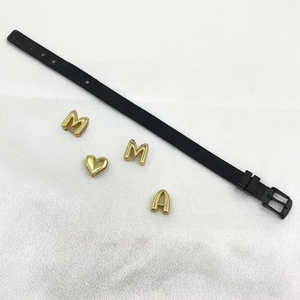Detail view of black stainless steel mesh strap with gold DIY initial letters and heart charm