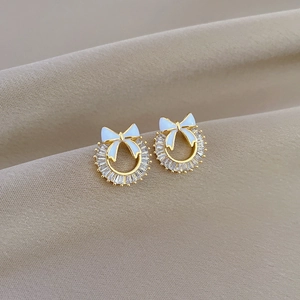 Close-up of gold hoop earrings featuring a white bow and micro-set baguette zirconia