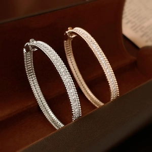 Detail of silver and gold pave-set zircon bracelets with secure clasp on brown velvet