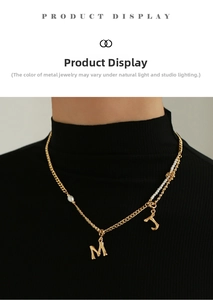 Golden bamboo style letter M and J pendants on a delicate pearl necklace worn by a model