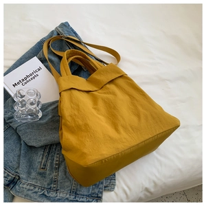 Detailed texture of ginger yellow nylon tote bag with wide strap on a casual background