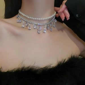 Dettaglio di una collana a doppio strato con perle bianche e pendenti in zircone
