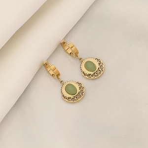 Detailed view of gold hoop earrings with green oval stone and filigree on white silk