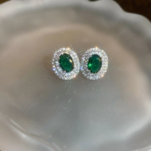 Macro shot of oval green gemstone earrings with double halo zircon pave setting