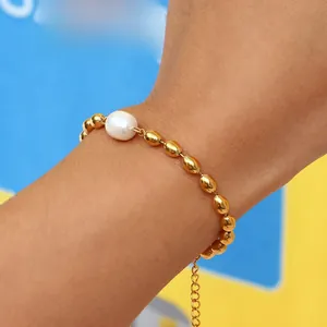 Detail of golden beaded bracelet with white pearl on wrist over blue and yellow background
