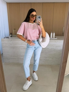 Détail du t-shirt à rayures roses et du jean bleu clair avec ourlet effiloché aux pieds