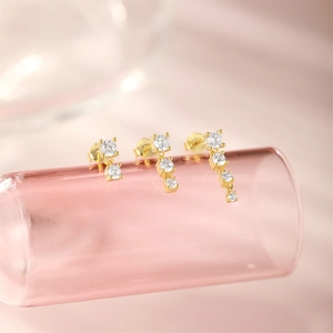 Close-up of gold silver stud earrings set with multiple clear cubic zirconia stones
