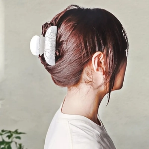 Pince à cheveux en acétate blanc avec lettrage Baby en strass portée par un modèle