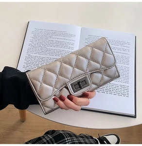 Detail of silver metallic quilted texture and dark nickel turn-lock on a fashion clutch