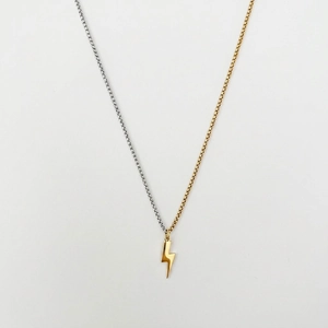Detail of two-tone 18K gold and silver stainless steel chain with lightning bolt charm