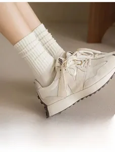 Détail de chaussettes en maille côtelée crème montrant la texture et la coupe plissée