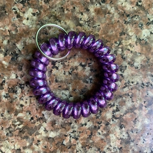 Macro shot of purple spiral telephone cord keychain with silver ring on marble