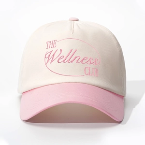 Detail of embroidered The Wellness Club logo on cream and pink cotton baseball cap