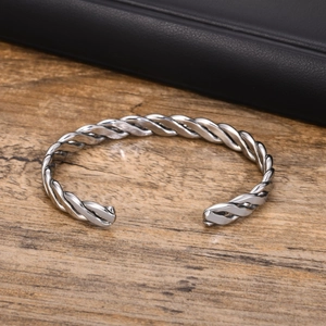 Macro view of silver twisted cable bracelet with vintage finish on wood surface