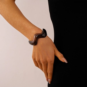 Close-up of amber resin wavy bangle with tortoiseshell pattern on model's wrist