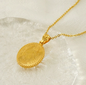 Macro shot of gold oval religious pendant with embossed Latin lettering on a textured plate
